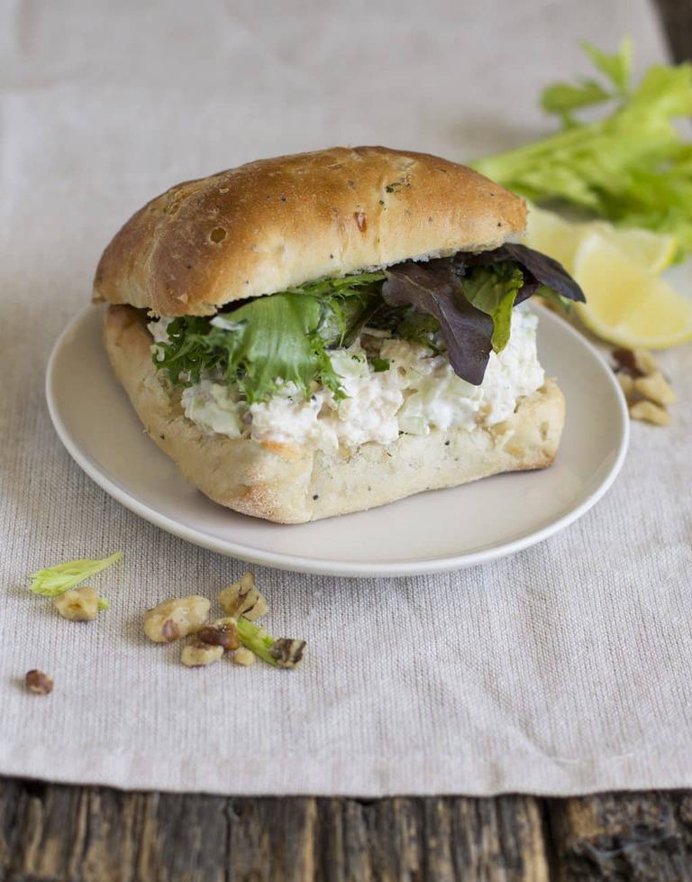 a chicken salad sandwich on a small plate on a white napkin