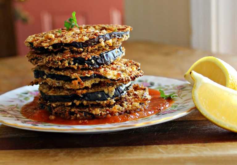 eggplant stacks on a plate with lemon wedges on the side