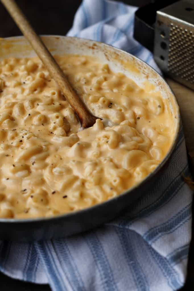a skillet of macaroni and cheese with a spoon resting in the center