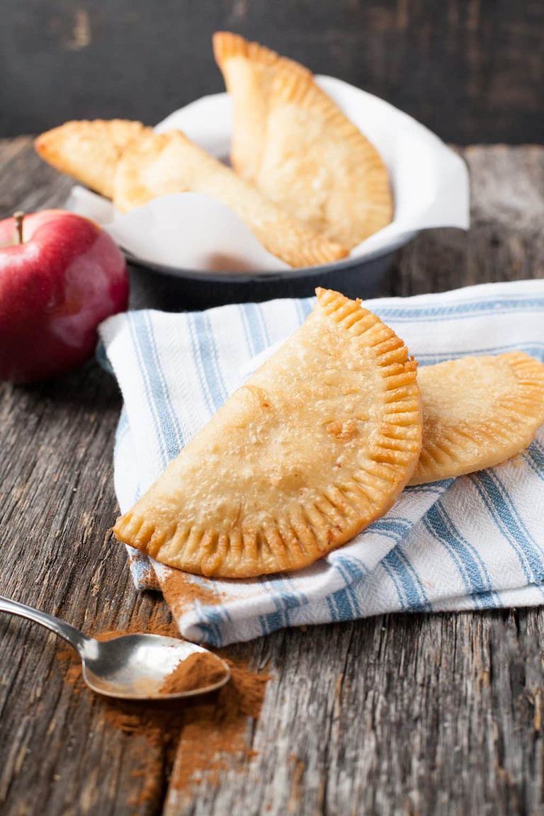 two fried apple pies on a blue napkin