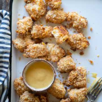 a platter of baked chicken nuggets with honey mustard and a fork
