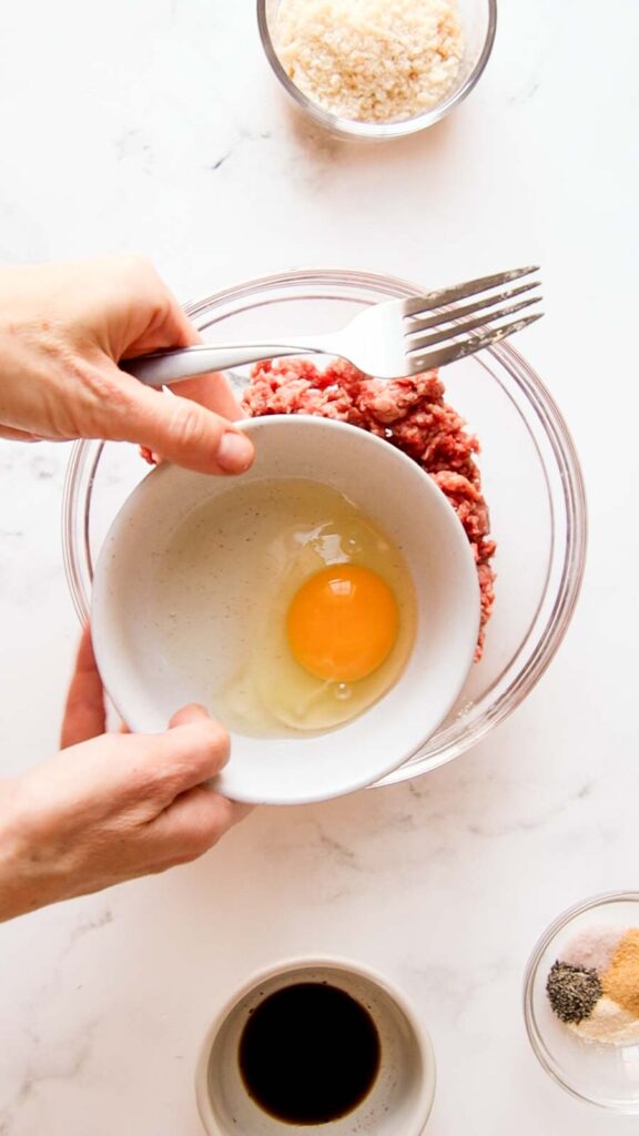 an egg in a bowl held over a bowl of ground beef