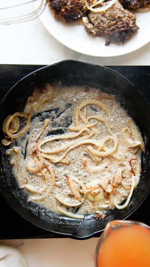 a skillet with flour and onions in beef drippings and broth in a glass to be added 