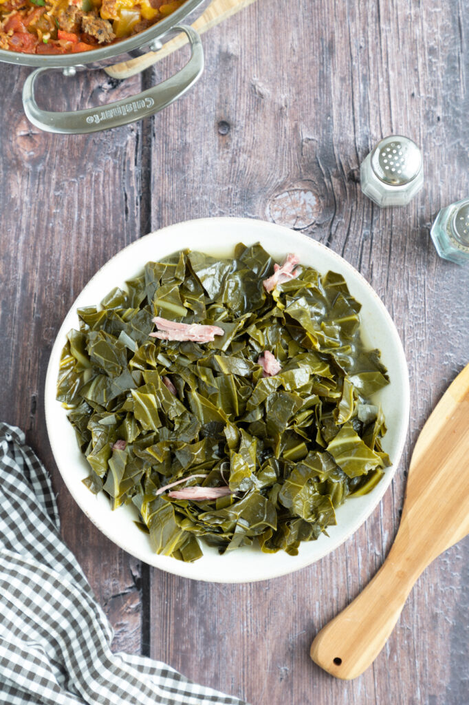 finished collard greens in a bowl on a table with salt and pepper