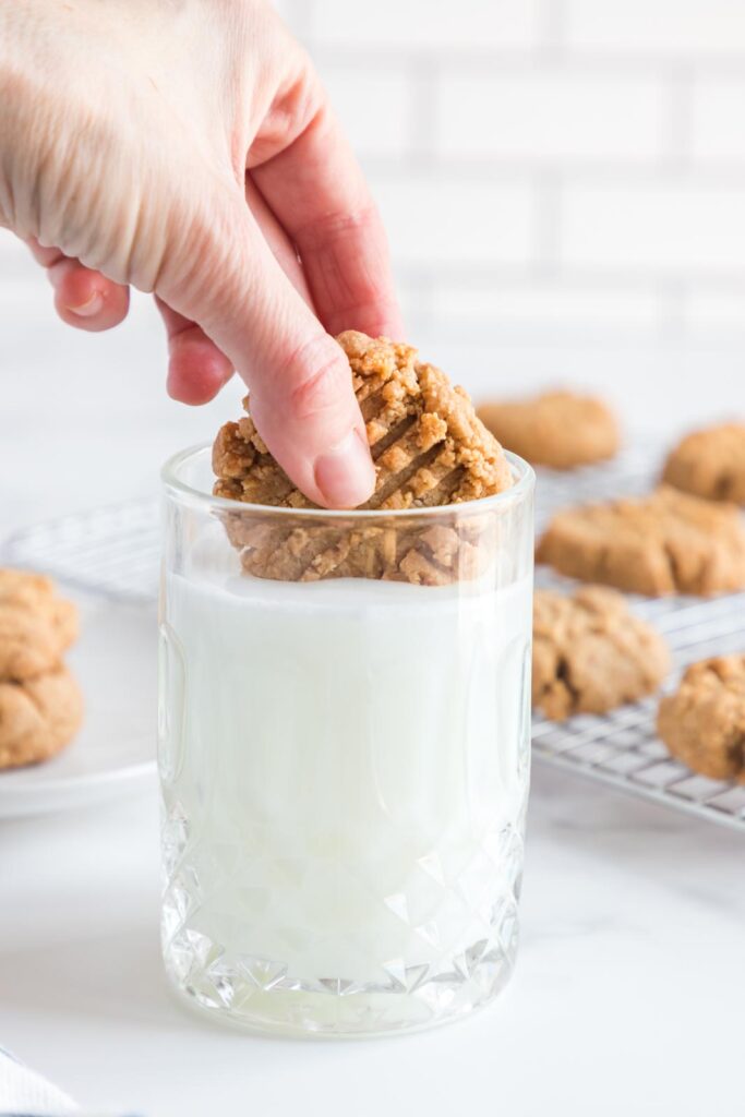 a cookie being dunked in a glass of milk on a table 