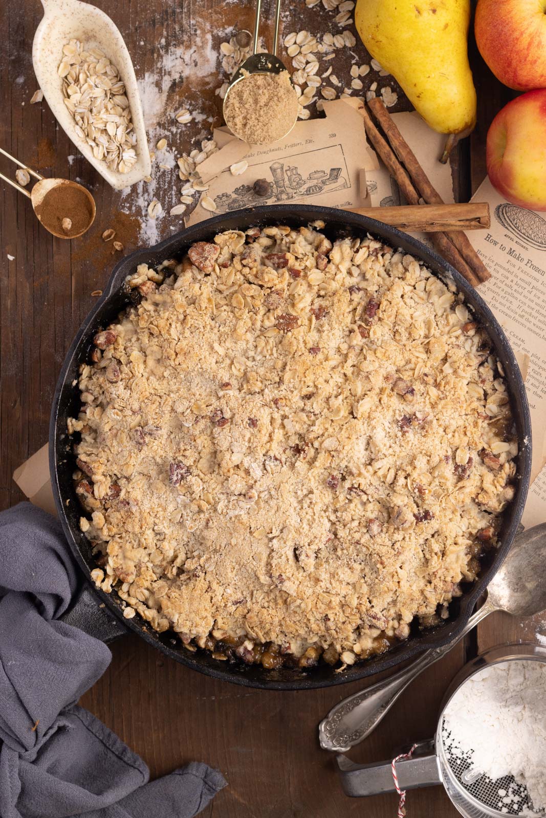 a skillet of unbaked apple pear crisp with the crisp topping spread on the fruit