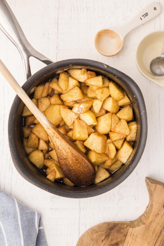 a pot with cooked apples and a spoon in the pot on a table