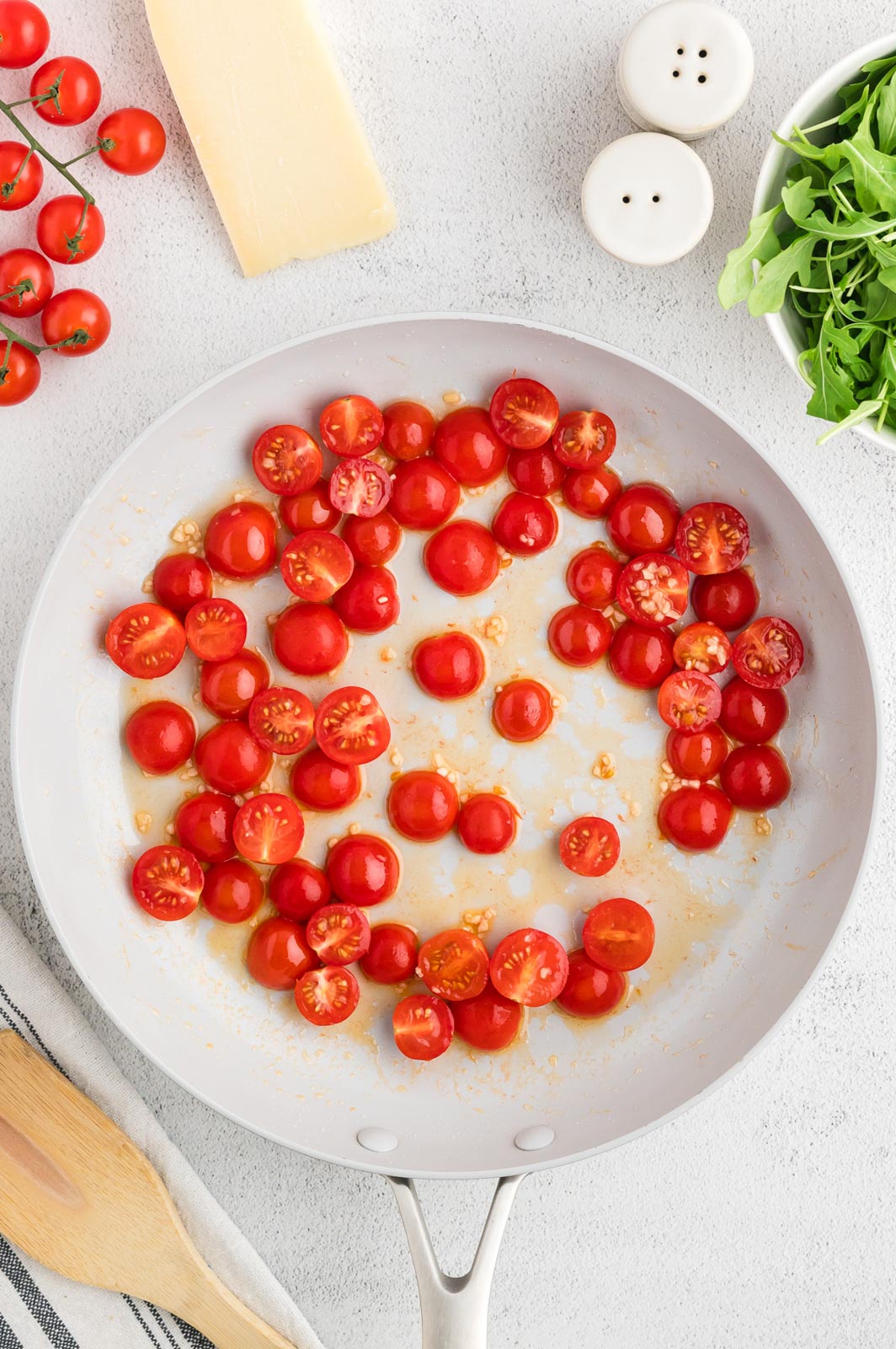 a skillet with cherry tomatoes sauteeing in bacon grease 