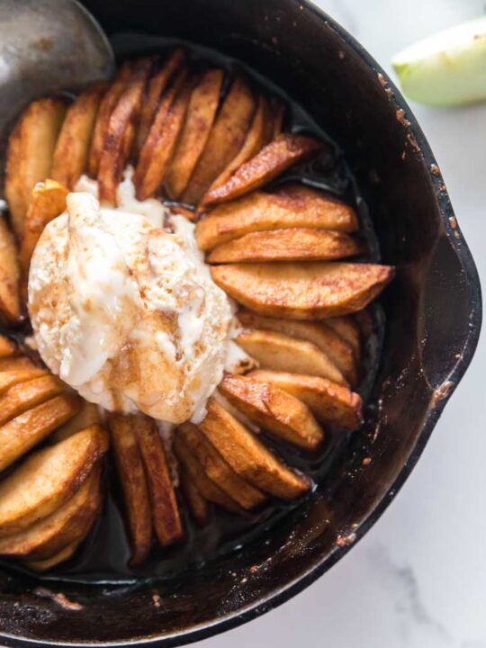 a skillet of baked apple slices in a skillet with ice cream