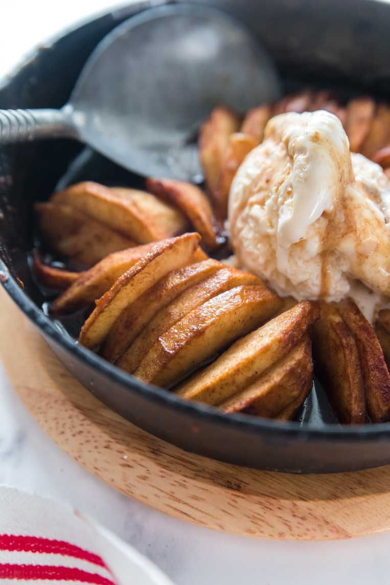 skillet of sliced apples with ice cream and a spoon