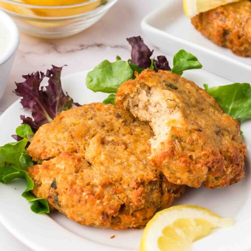 two salmon patties on a plate with greens