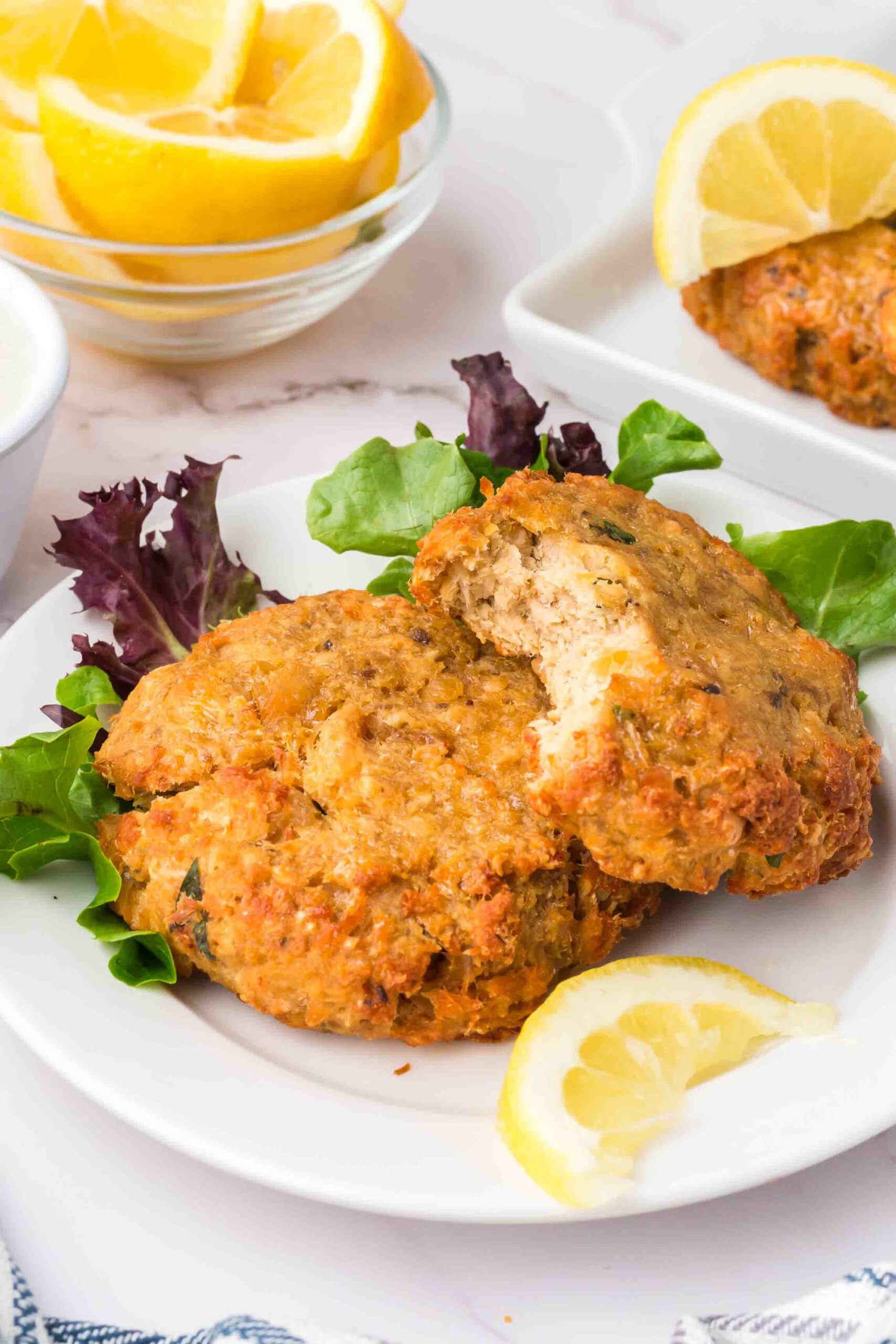 two salmon patties on a plate with greens 