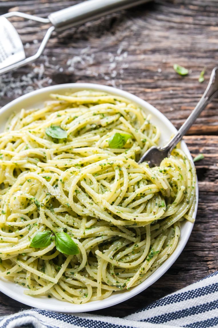 a plate of spaghetti with pesto with a fork