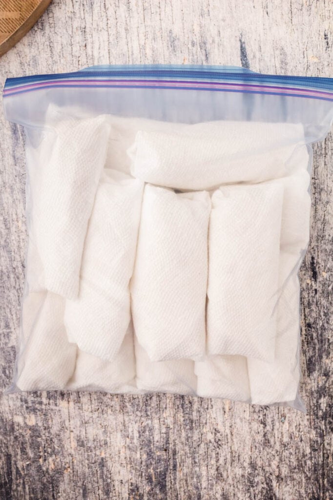 A large zip lock bag with several burritos wrapped in paper towels ready for the refrigerator or freezer 
