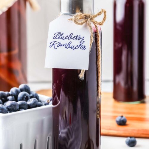 a tall glass bottle of finished blueberry kombucha