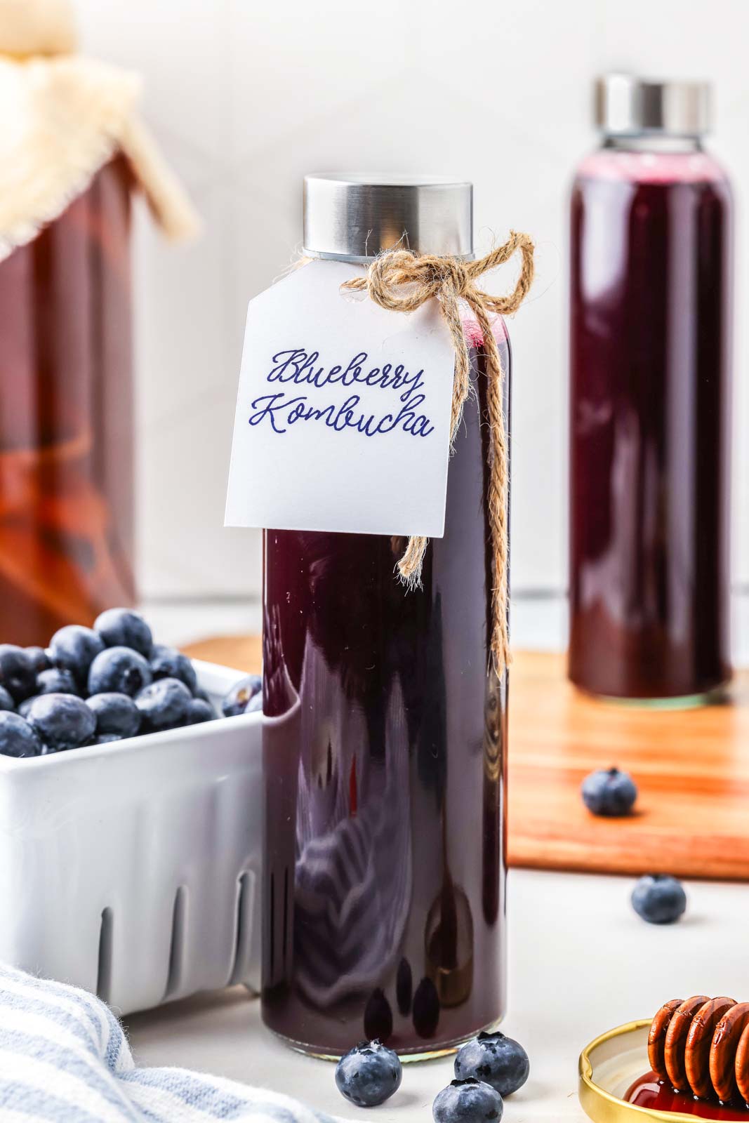 a tall glass bottle of finished blueberry kombucha 