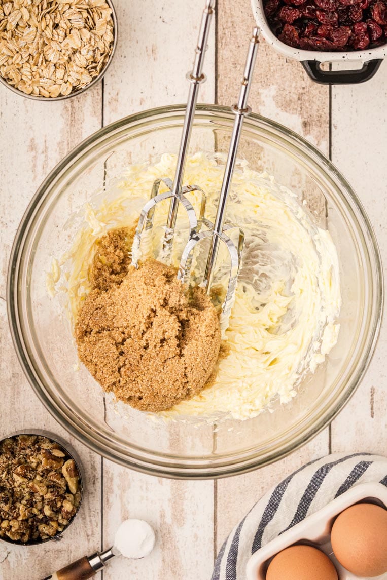 a bowl with butter and brown sugar with a hand mixer