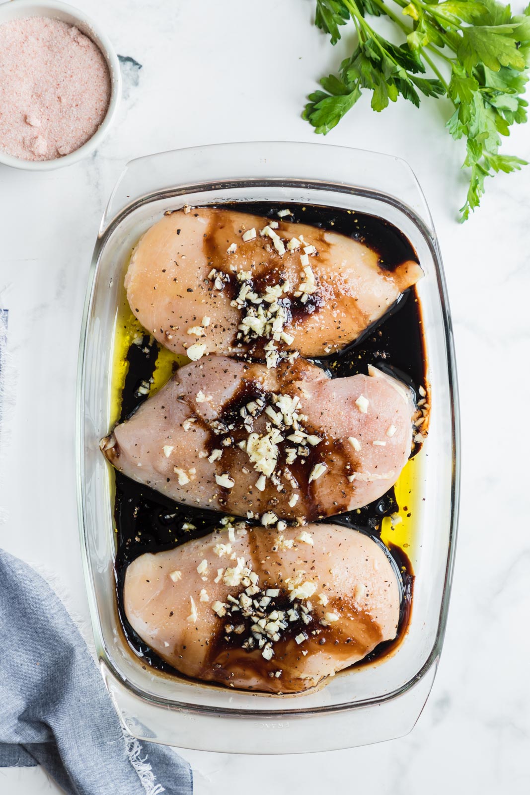 three chicken breasts with marinade ingredients being added 