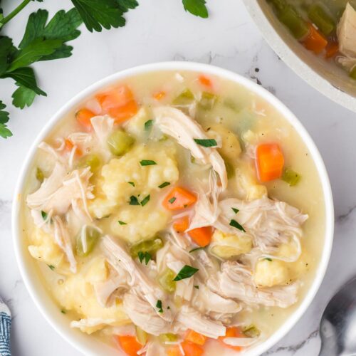 a bowl of easy southern chicken and dumplings on a table with parsley