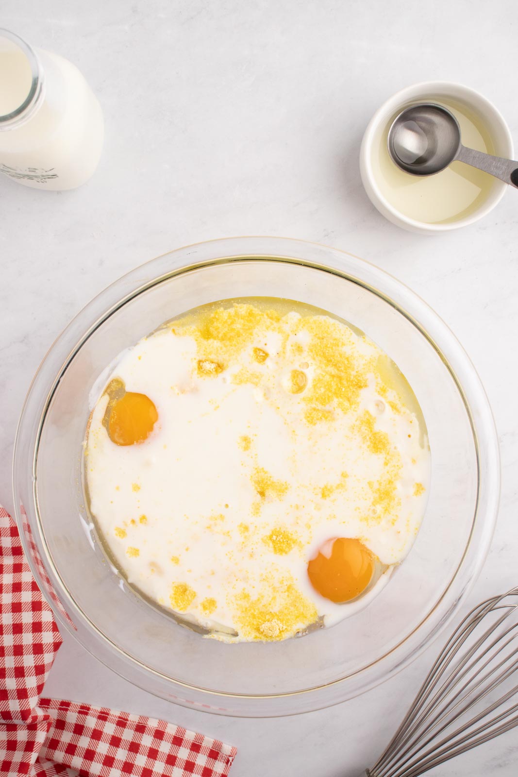 Adding the buttermilk to eggs, oil, and sefl-rising cornmeal mix to make cornbread cakes.