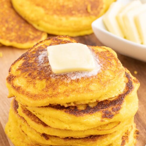 A stack of cornbread cakes with a pad of butter on top.