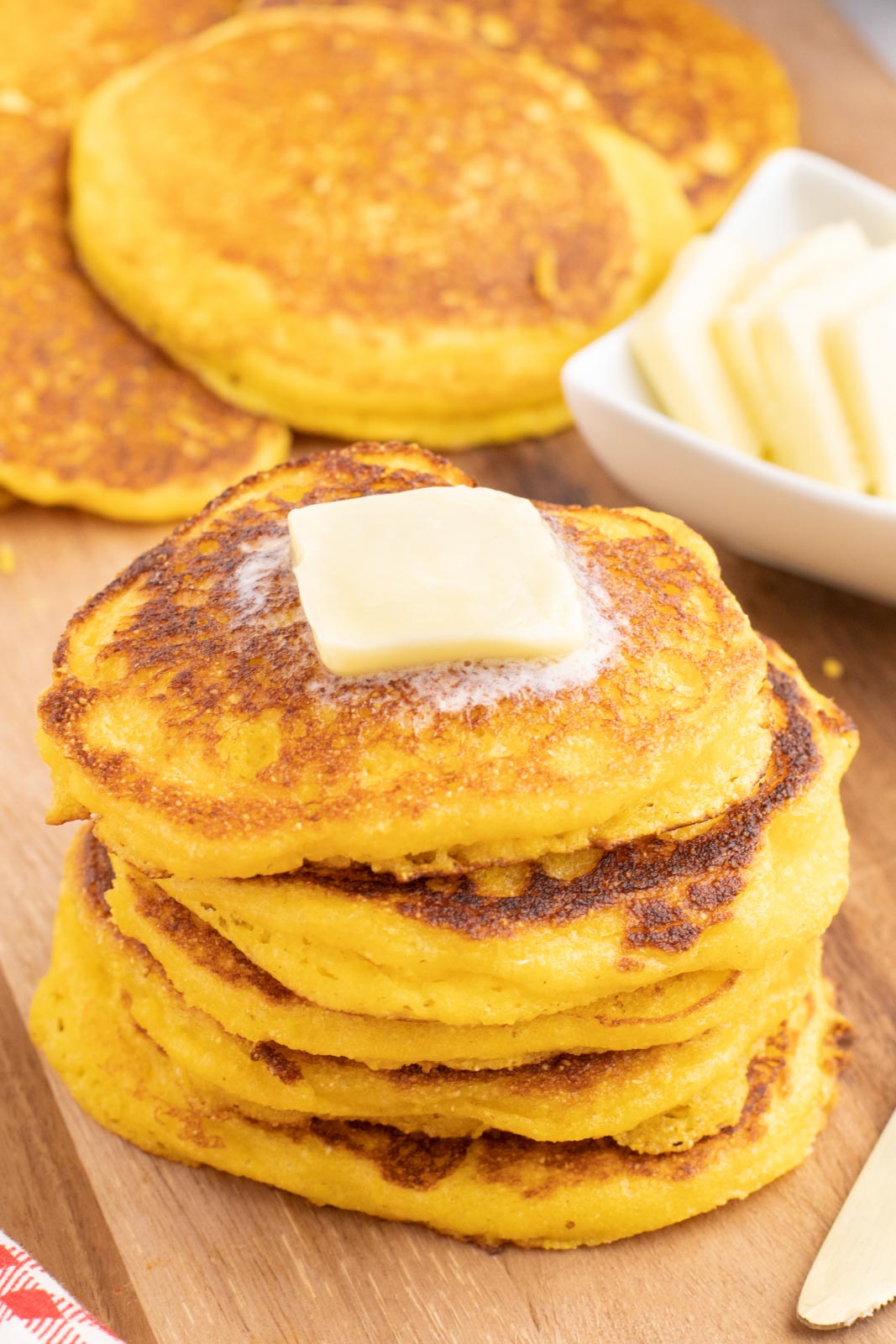 A stack of cornbread cakes with a pad of butter on top.