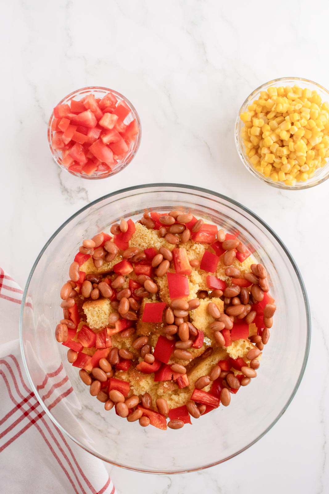 Layering tomatoes and pinto beans over cubed cornbread in a trifle dish.