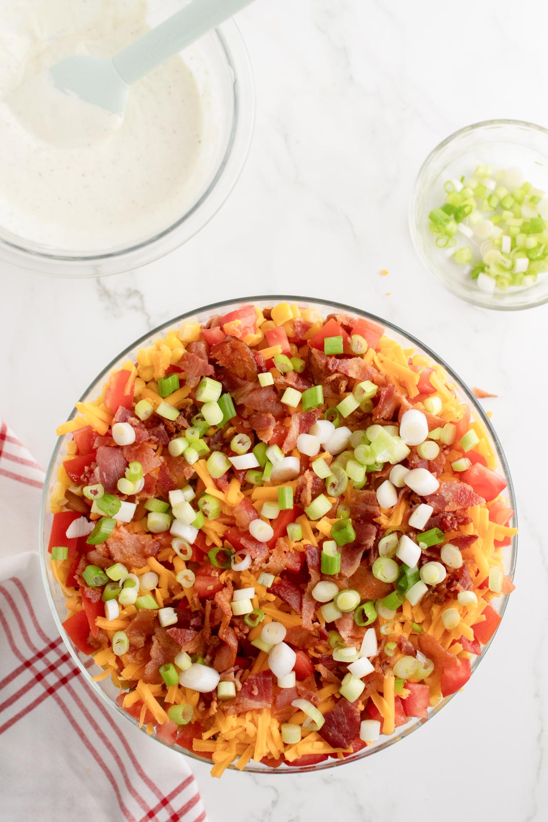 Overhead image of cornbread salad loaded with bacon, cheese, scallions, and more.