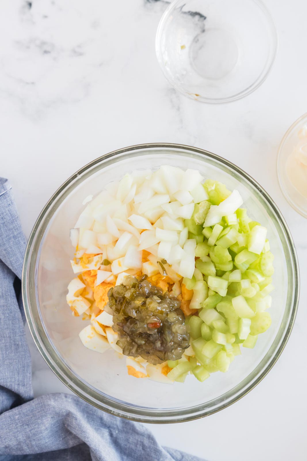 a bowl with onions, eggs, celery and sweet pickle relish to be mixed together 