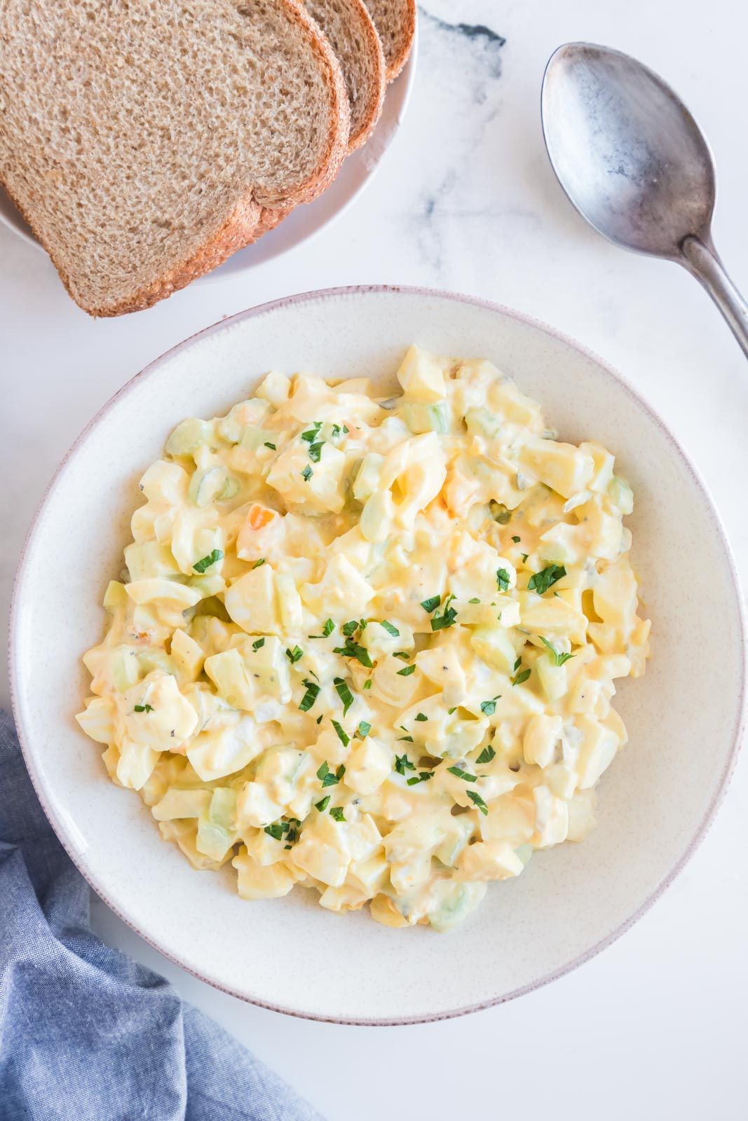 a bowl of mixed egg salad on a table with bread on the side 
