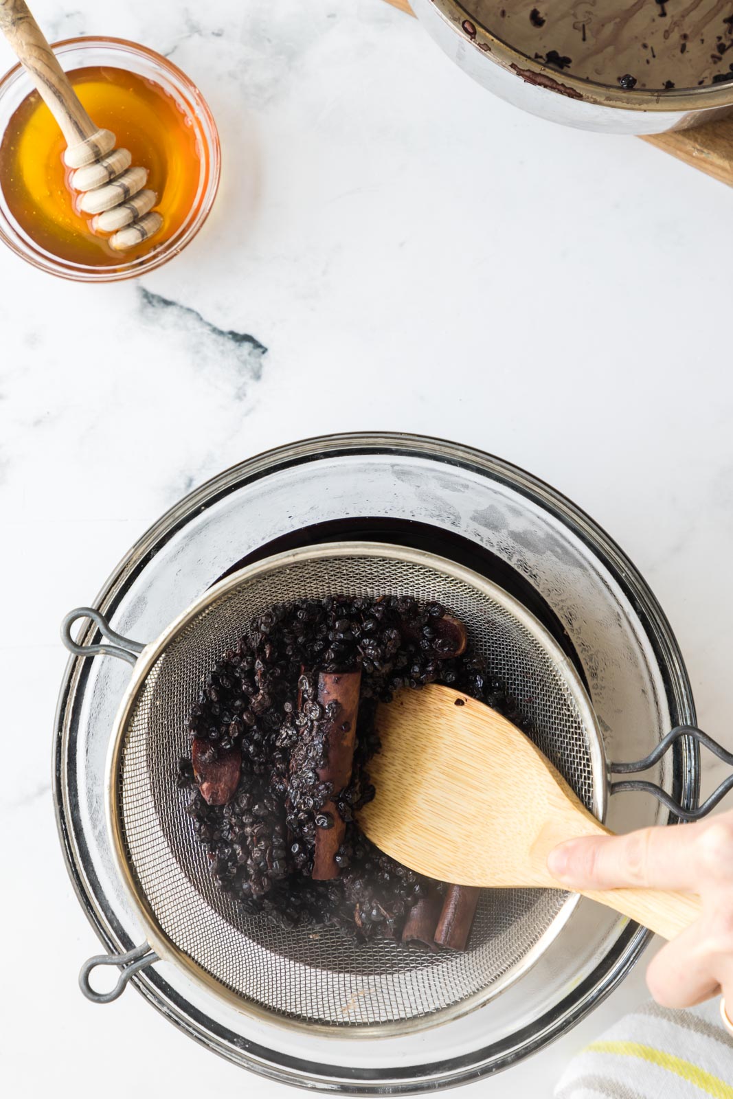 a spatula pressing cooked berries through a sieve 