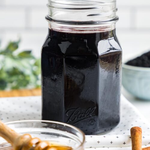 a jar of elderberry syrup on a table