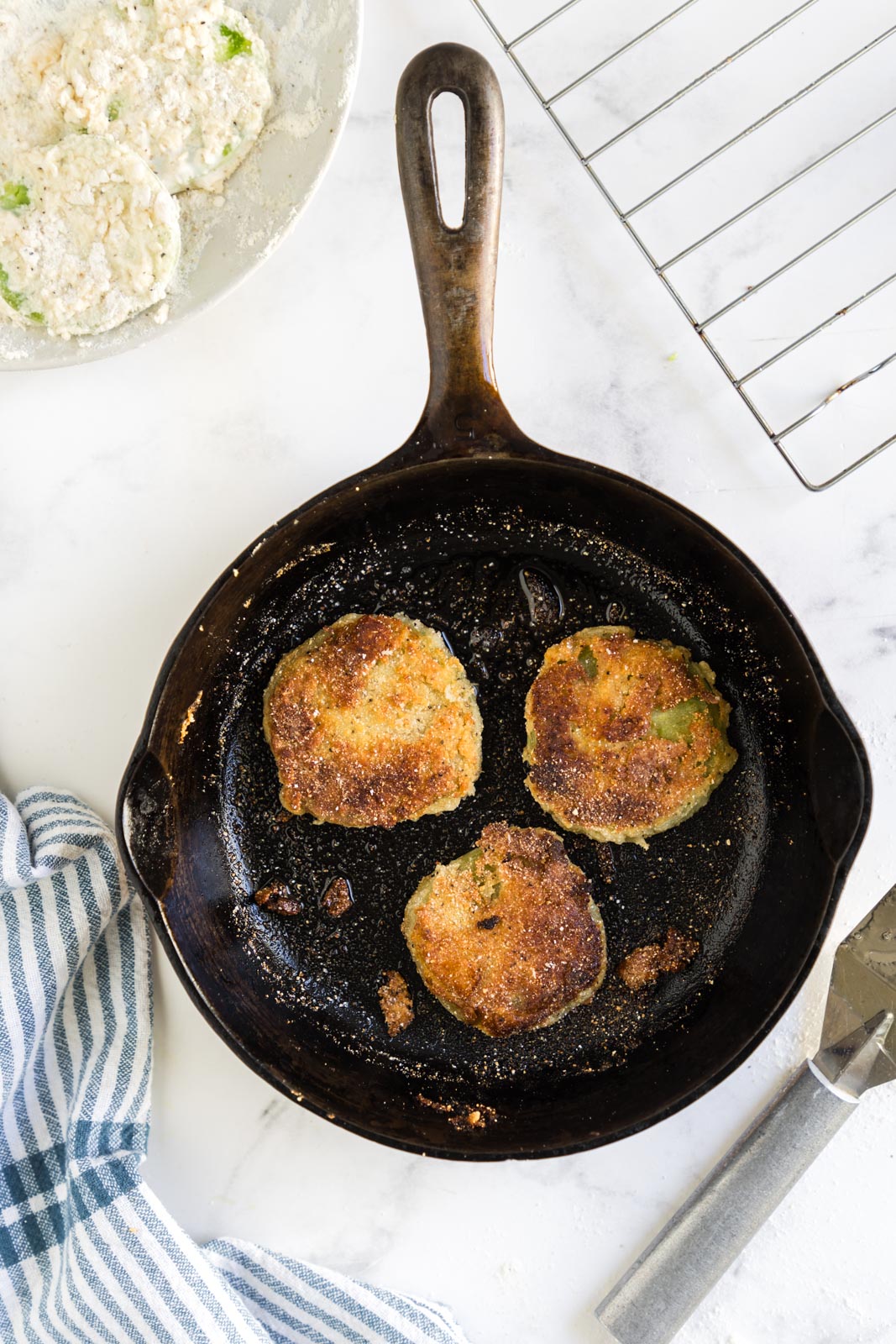 a skillet with green tomatoes frying inside