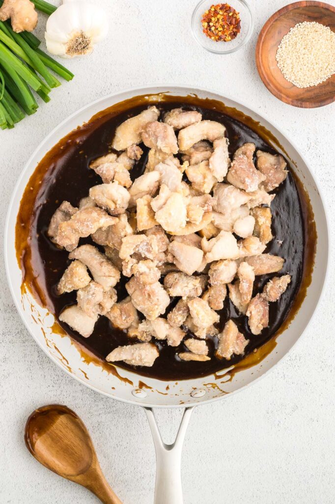 chicken added to general tso sauce in a skillet