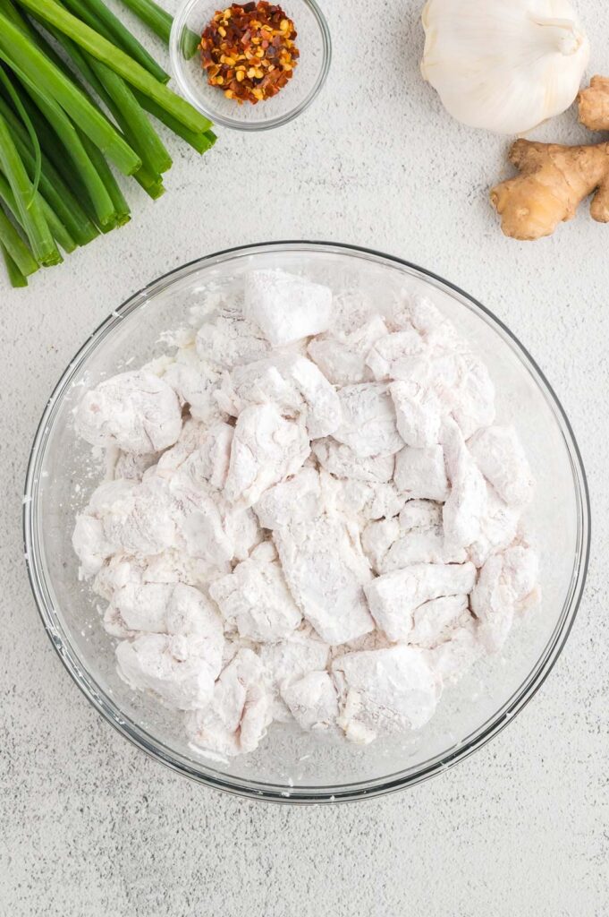 a bowl of chicken pieces tossed in cornstarch