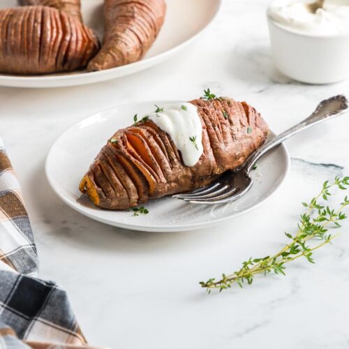 hasselback sliced sweet potato baked and topped with butter and savory herbs