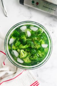 a bowl of ice water with broccoli cooling after blanching