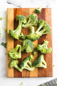 a cutting board with broccoli florets to be blanched