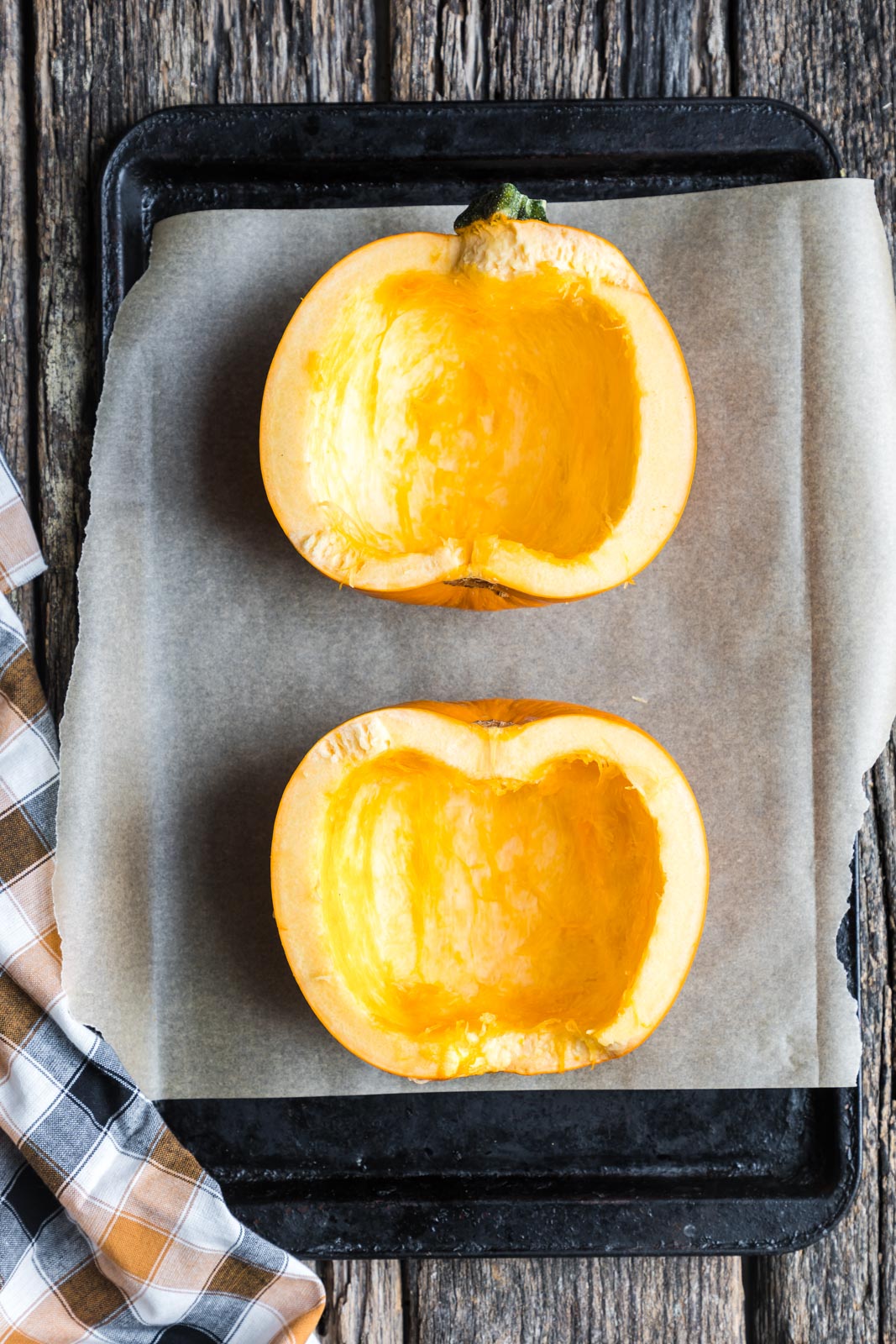 2 halves of a sugar pumpkin cut-side up on a baking sheet. 
