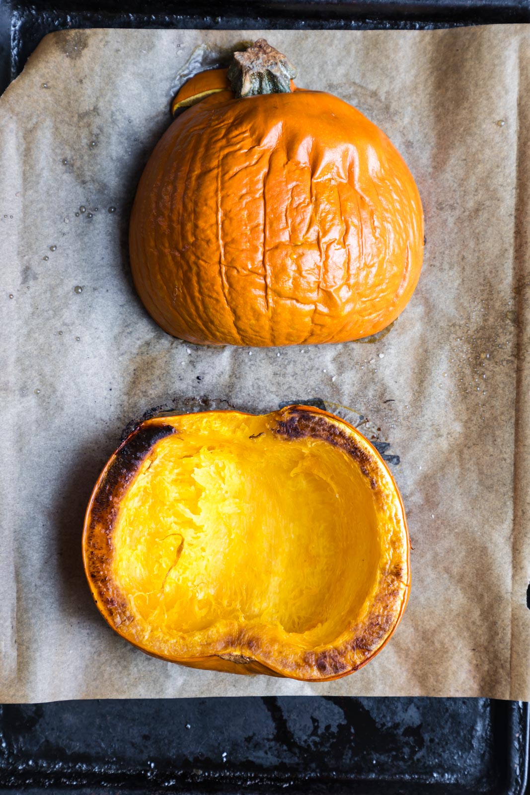 2 halves of a roasted sugar pumpkin. One is cut-side down and one is cut-side up.