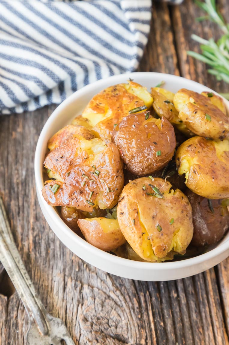 a bowl of little potatoes with rosemary and butter