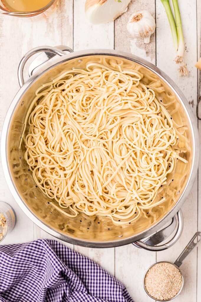 a colander of cooked pasta on a table