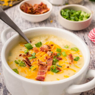 A bowl of potato soup with a spoon in it