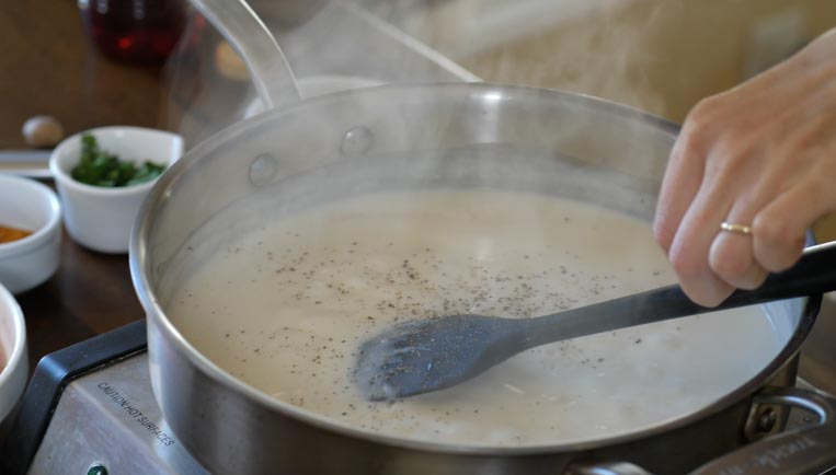 a pot of bechamel sauce being stirred with a spatula