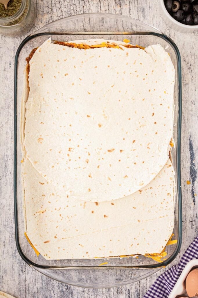 flour tortillas layered on top in 9x13 pan