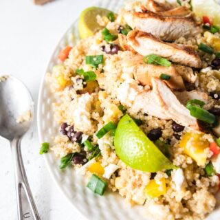 a white platter of Mexican quinoa salad with a spoon on the side.