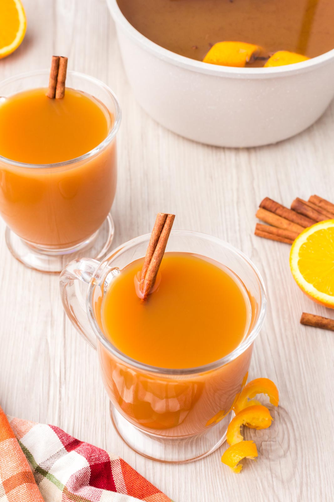 two mugs of mulled cider with  cinnamon sticks 