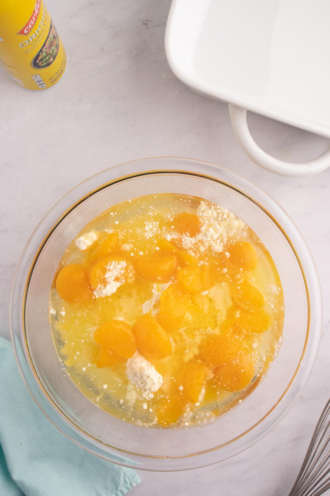 a bowl of cake mix with mandarin oranges added but not mixed in yet