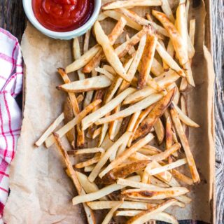 a cookie sheet of baked fries with ketchup