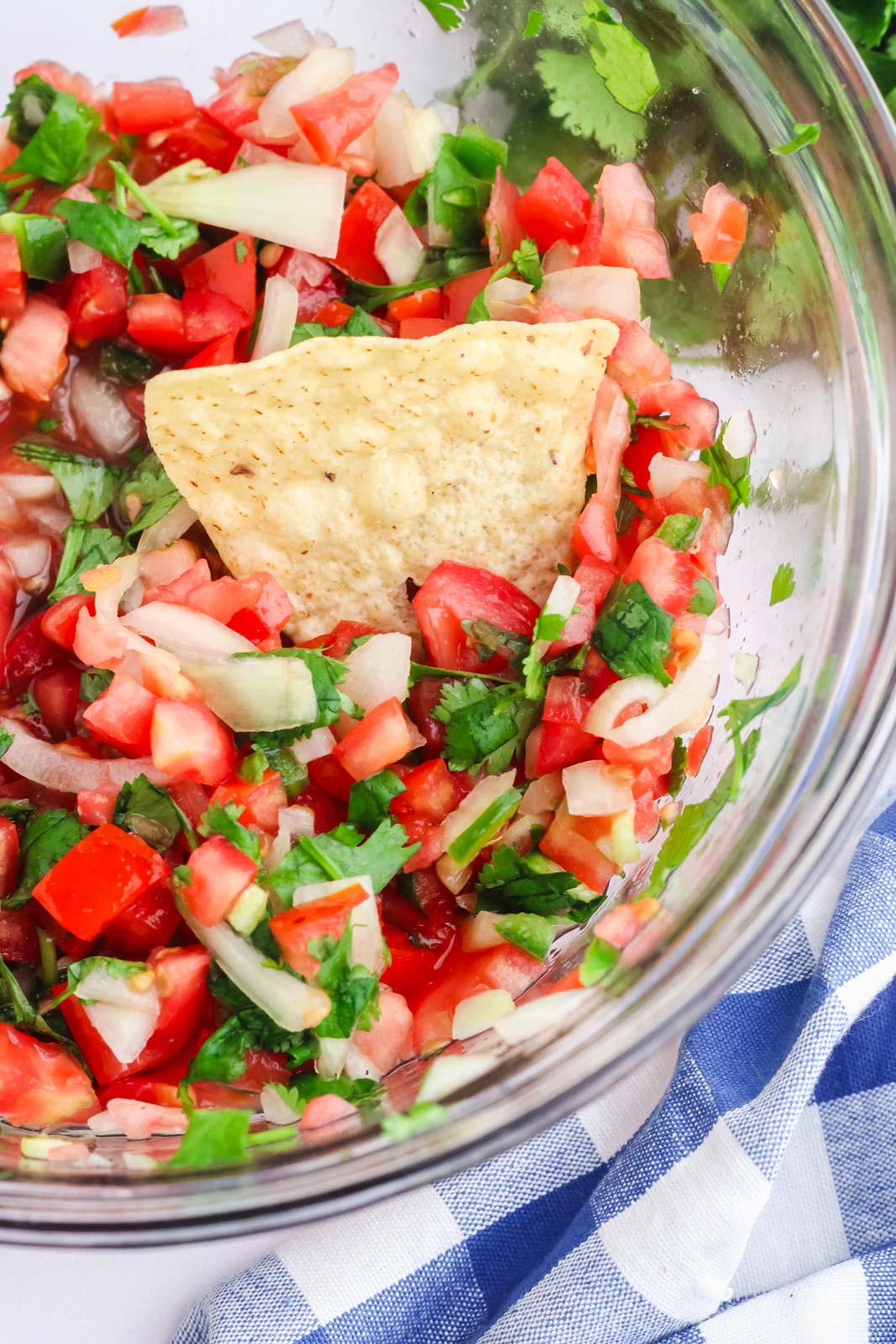 a bowl of finished pico de gallo with a chip in the bowl